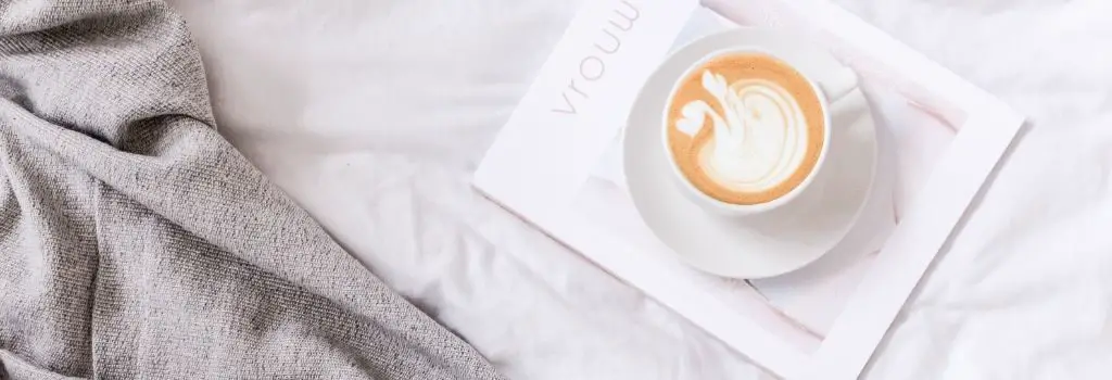 coffee sitting on white magazine in a bed