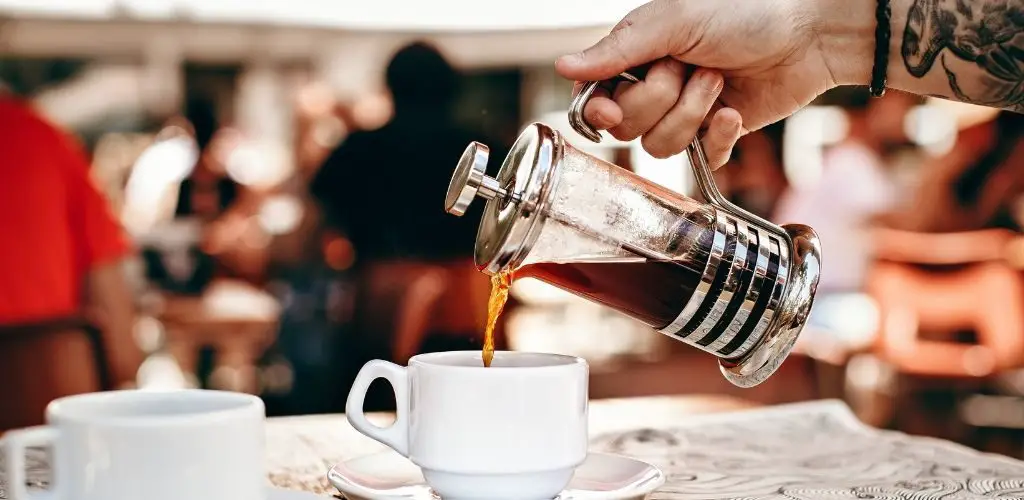 Man pouring french press coffee into mug, specialty coffee with a french press