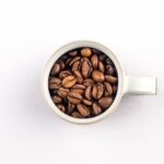 Small espresso mug filled with roasted coffee beans