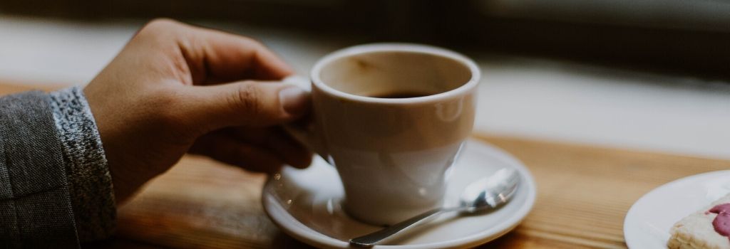 person holding espresso cup with coffee inside