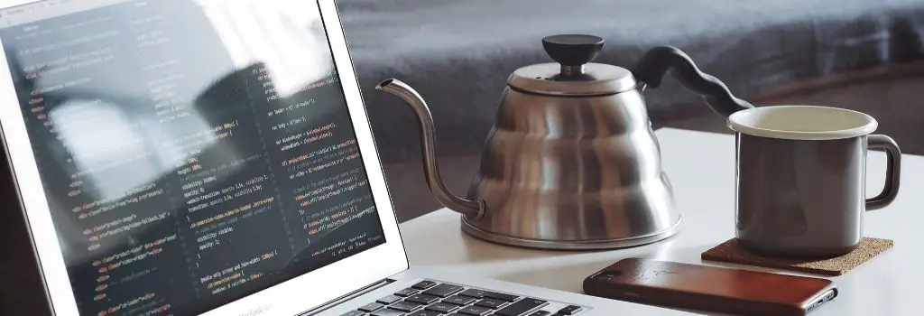 gooseneck kettle next to laptop and coffee mug