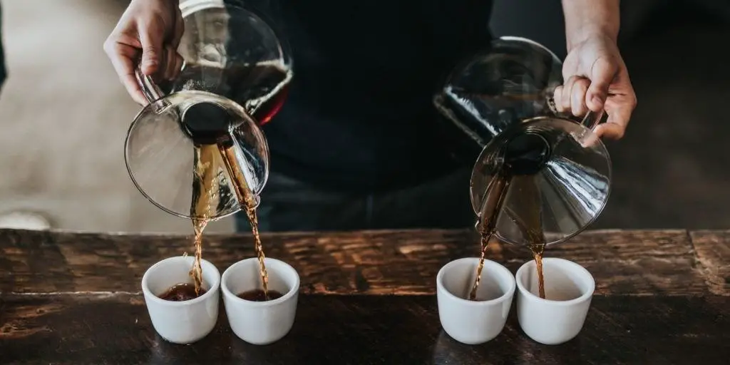 person pouring coffee from two chemex into cups