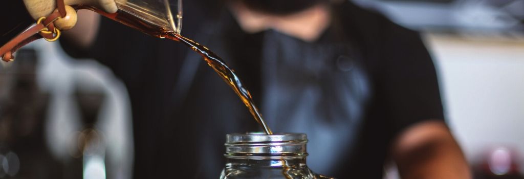 pouring drip coffee into jug from chemex