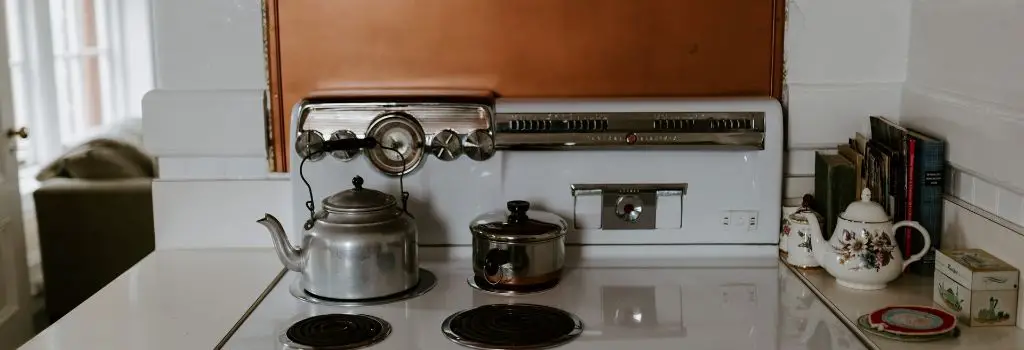 oven stove top with sauce pan and kettle on elements