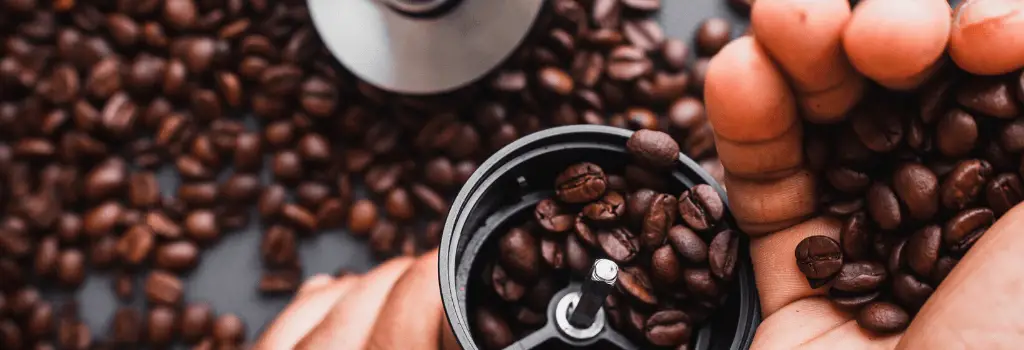 putting roasted coffee beans into coffee grinder