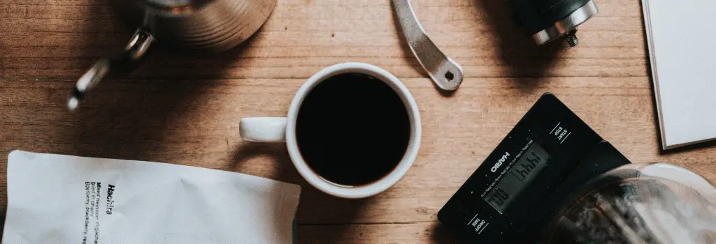 coffee in white cup with coffee equipment around it, strongest coffee beans, strong coffee