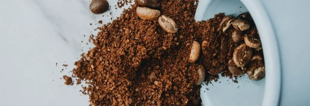 ground coffee beans spilling out of cup